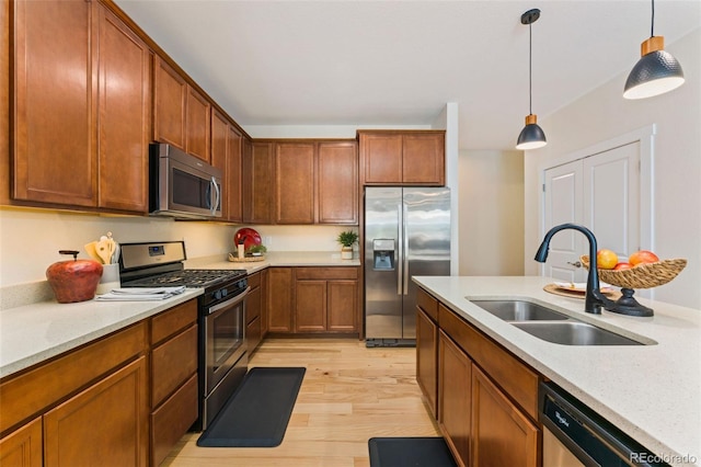 671 Robert St, Longmont, CO 80503 - kitchen with stainless steel appliances, a sink, light wood-style flooring, pendant lighting, and brown cabinetry