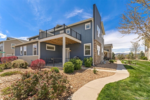 671 Robert St, Longmont, CO 80503 - back of house with a balcony, stone siding, and a yard