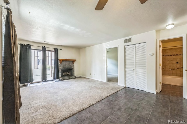 225 E 8th Ave Unit 10, Longmont, CO 80504 - unfurnished living room with ceiling fan, a textured ceiling, a brick fireplace, and dark colored carpet