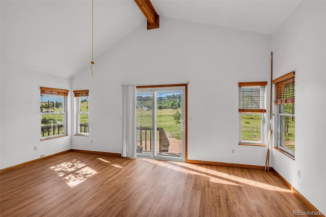 spare room featuring high vaulted ceiling, light hardwood / wood-style flooring, and beam ceiling