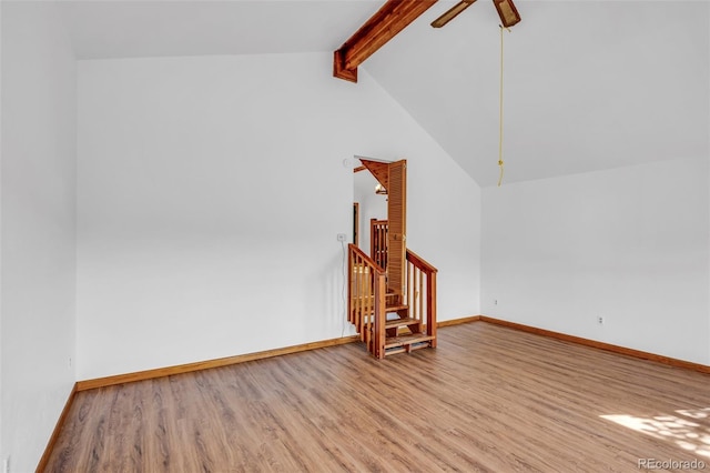 unfurnished living room with ceiling fan, lofted ceiling with beams, and wood-type flooring