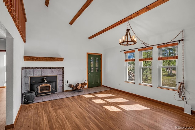 unfurnished living room featuring light hardwood / wood-style floors, beamed ceiling, a notable chandelier, high vaulted ceiling, and a wood stove