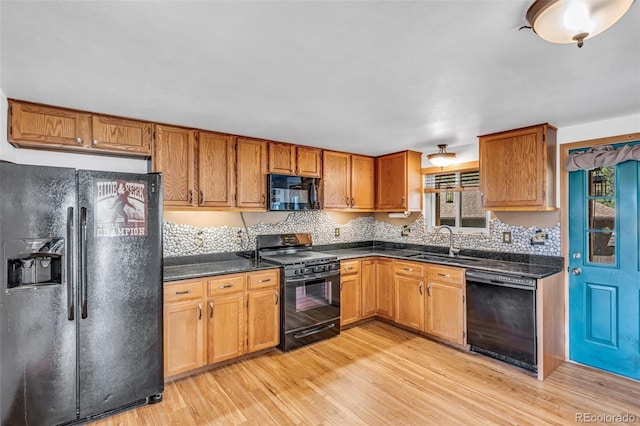 kitchen with black appliances, tasteful backsplash, light hardwood / wood-style flooring, and sink