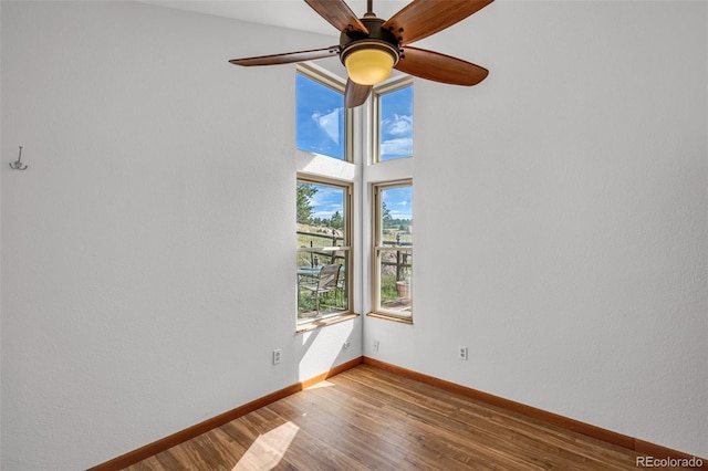 unfurnished room with ceiling fan, a wealth of natural light, and wood-type flooring