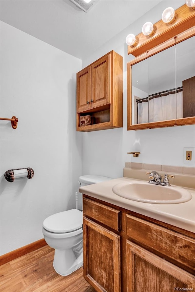 bathroom featuring toilet, vanity, walk in shower, and hardwood / wood-style floors