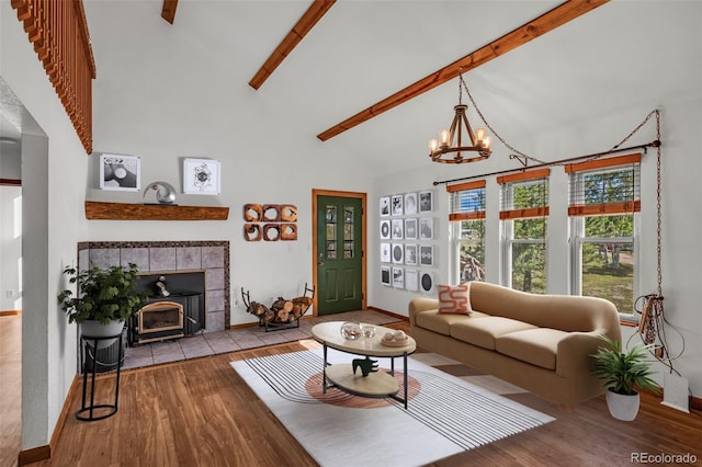 living room with high vaulted ceiling, light wood-type flooring, beam ceiling, an inviting chandelier, and a fireplace