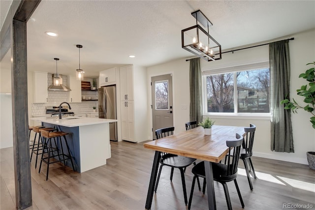 dining room with a textured ceiling, light wood finished floors, baseboards, and recessed lighting