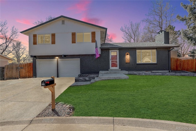 tri-level home featuring a front yard, concrete driveway, brick siding, and fence