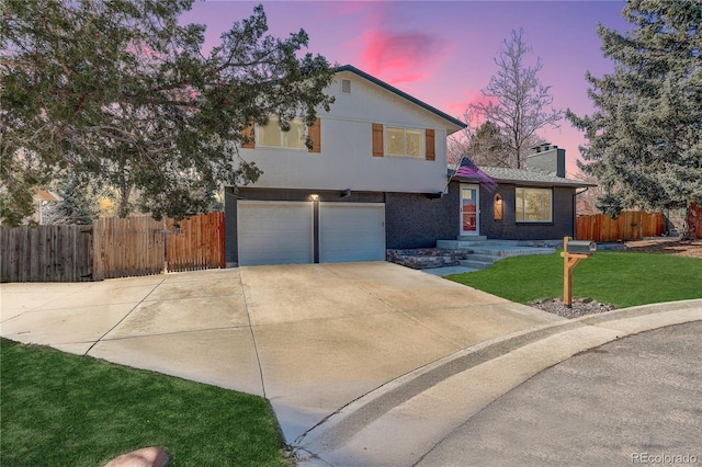 split level home with driveway, fence, and brick siding