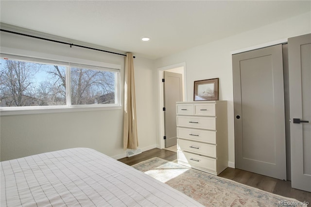 bedroom with dark wood-style flooring, visible vents, and baseboards