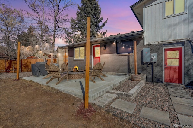 patio terrace at dusk featuring a fire pit and fence