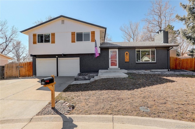 split level home featuring concrete driveway, brick siding, a chimney, and fence