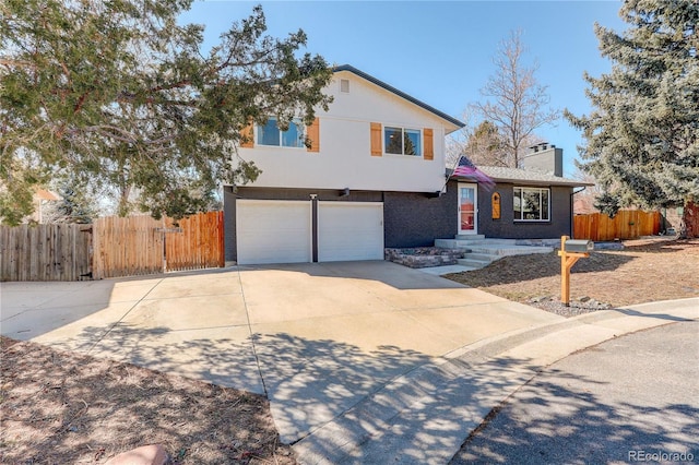 split level home with a garage, brick siding, fence, concrete driveway, and a chimney