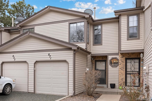 townhome / multi-family property with a garage and brick siding