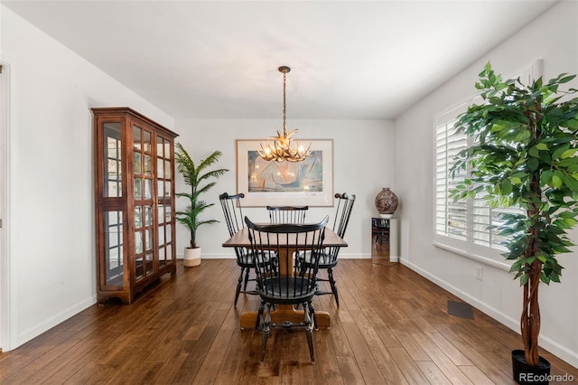 dining space featuring dark wood-style flooring, baseboards, and an inviting chandelier