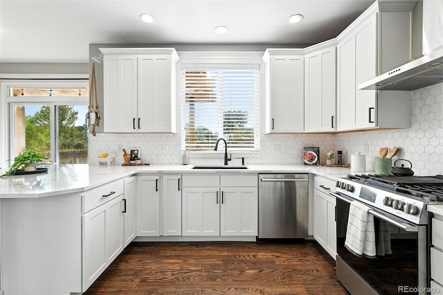 6039 Quay Ct, Arvada, CO 80003 - kitchen featuring stainless steel appliances, wall chimney range hood, dark wood-type flooring, tasteful backsplash, and white cabinets