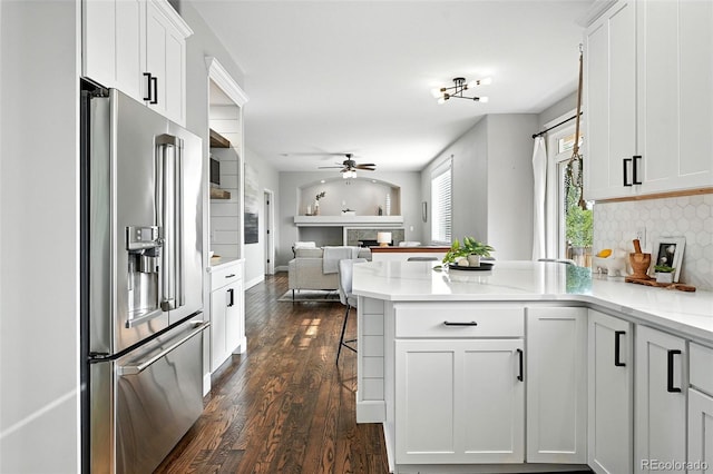 6039 Quay Ct, Arvada, CO 80003 - kitchen featuring high end fridge, a peninsula, open floor plan, a ceiling fan, and dark wood-style floors