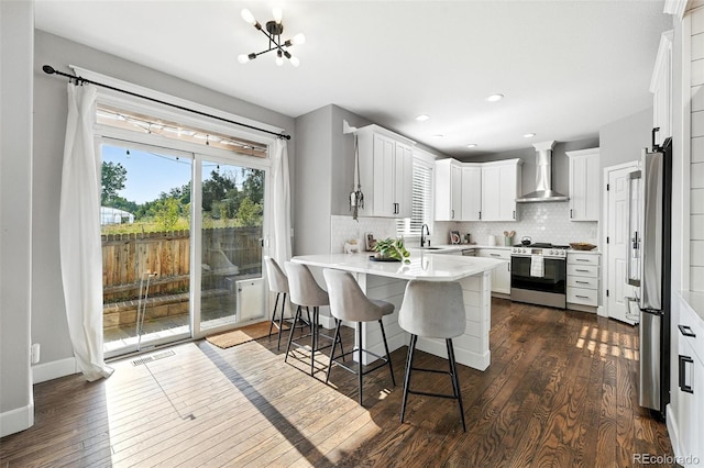 6039 Quay Ct, Arvada, CO 80003 - kitchen with appliances with stainless steel finishes, wall chimney range hood, a peninsula, healthy amount of natural light, and recessed lighting