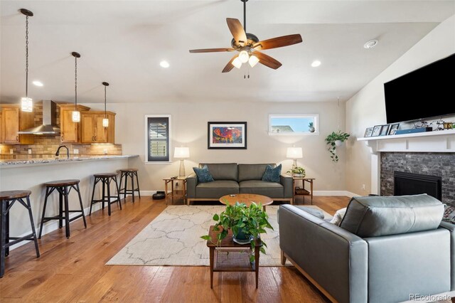 12441 Woodruff Dr, Colorado Springs, CO 80921 - living area featuring light wood-style floors, a ceiling fan, baseboards, recessed lighting, and a fireplace