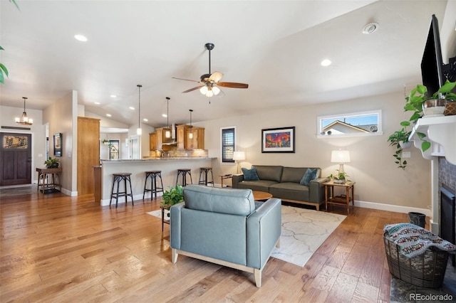 12441 Woodruff Dr, Colorado Springs, CO 80921 - living room with lofted ceiling, baseboards, ceiling fan, a fireplace, and light wood-style flooring