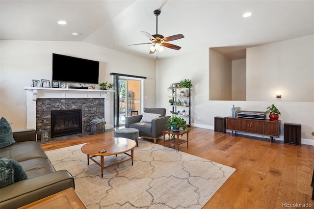12441 Woodruff Dr, Colorado Springs, CO 80921 - living area featuring wood finished floors, ceiling fan, a stone fireplace, vaulted ceiling, and baseboards