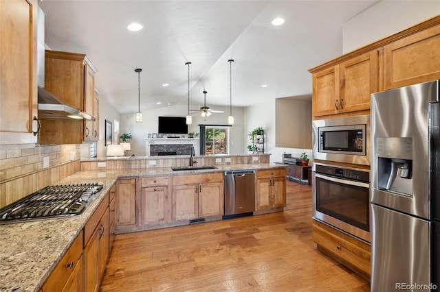 12441 Woodruff Dr, Colorado Springs, CO 80921 - kitchen with stainless steel appliances, a sink, a fireplace, ceiling fan, and a peninsula