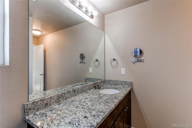 bathroom with a textured wall and vanity