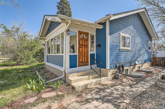 bungalow with a sunroom, fence, and entry steps