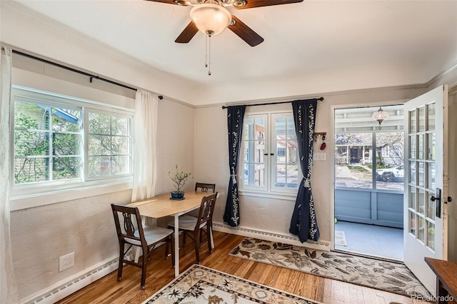 dining room featuring wood finished floors, baseboards, ceiling fan, a baseboard heating unit, and french doors