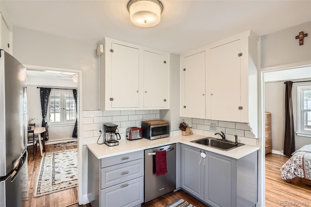 kitchen featuring gray cabinetry, appliances with stainless steel finishes, tasteful backsplash, and a sink