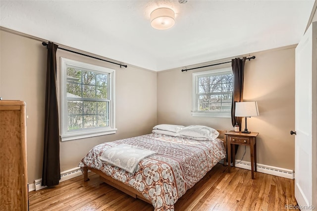 bedroom featuring baseboards, a baseboard radiator, multiple windows, and light wood-style flooring