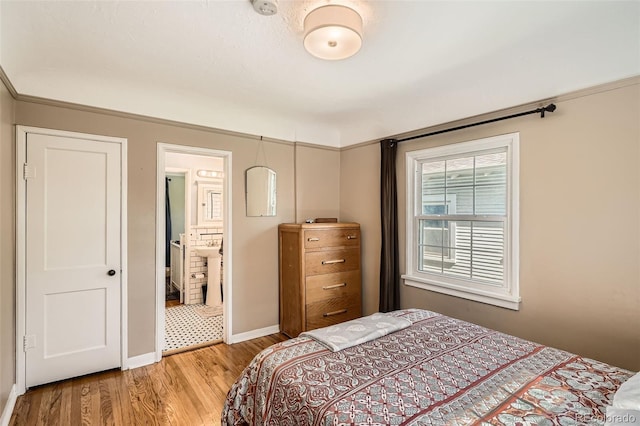 bedroom featuring baseboards, light wood-type flooring, and connected bathroom