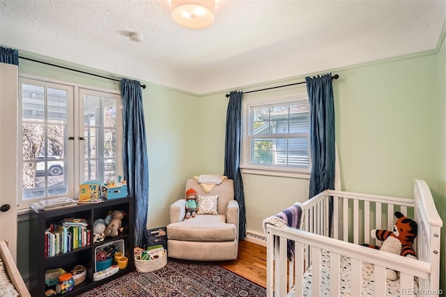bedroom featuring wood finished floors, baseboards, and a nursery area