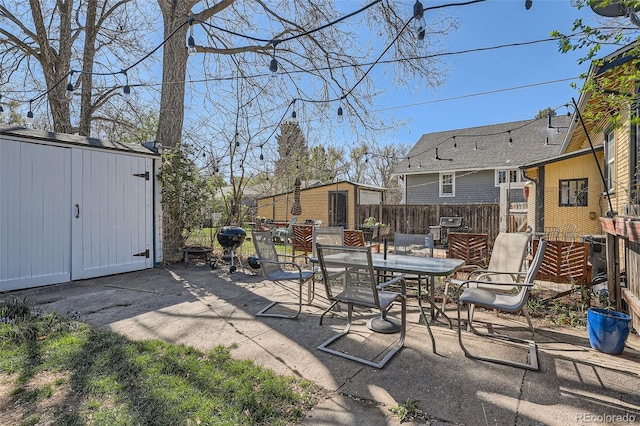 view of patio featuring outdoor dining area, a shed, an outbuilding, and fence