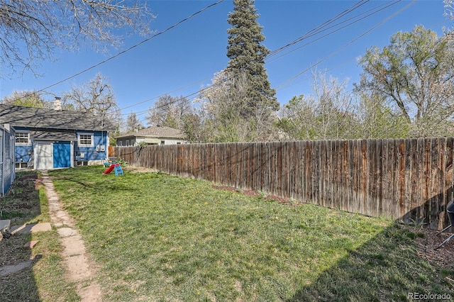 view of yard with an outdoor structure, a fenced backyard, and a storage unit