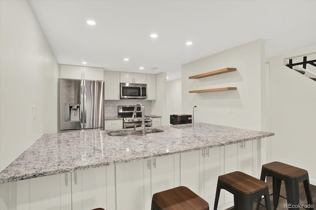 8055 E Colorado Ave Unit 8, Denver, CO 80231 - kitchen featuring appliances with stainless steel finishes, open shelves, decorative backsplash, a peninsula, and light stone countertops