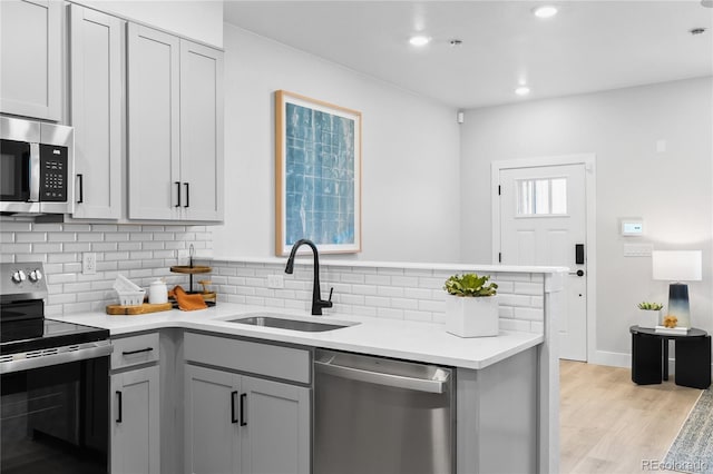 17137 W 91st Ln, Arvada, CO 80007 - kitchen featuring stainless steel appliances, backsplash, gray cabinetry, light countertops, and light wood-type flooring