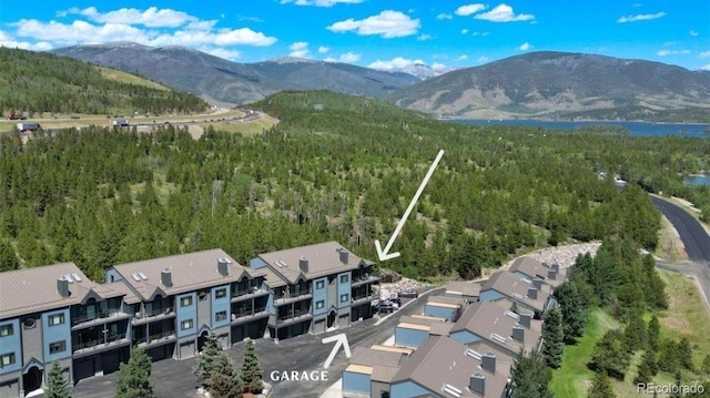aerial view of property and surrounding area with a forest, mountains, and nearby suburban area
