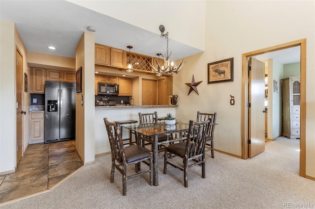 dining space with a chandelier, light colored carpet, and baseboards
