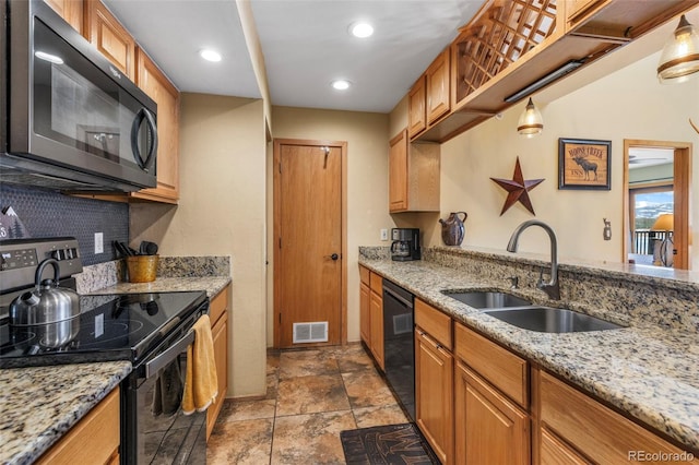 kitchen with black appliances, a sink, light stone counters, stone finish floors, and brown cabinets