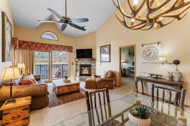 living area featuring high vaulted ceiling, carpet flooring, a stone fireplace, and a ceiling fan
