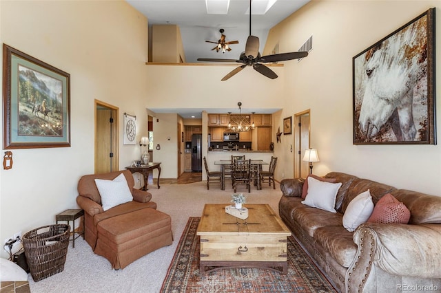 living area featuring a chandelier, light colored carpet, a ceiling fan, and a towering ceiling