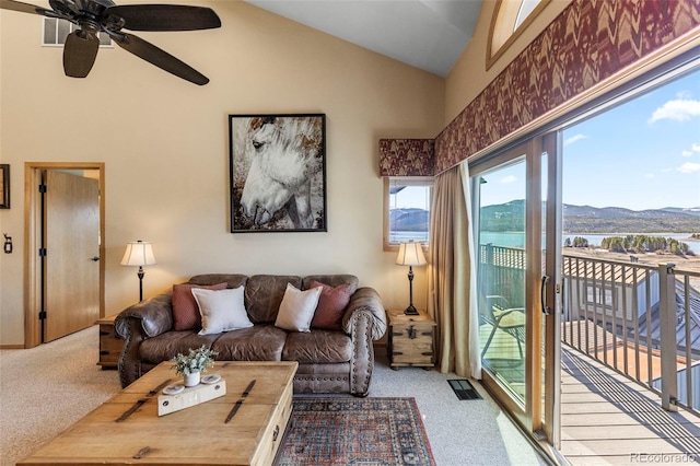 carpeted living room featuring ceiling fan, healthy amount of natural light, high vaulted ceiling, and a water and mountain view