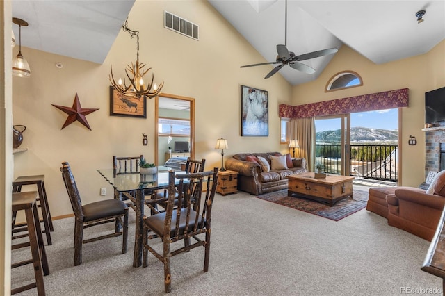 carpeted dining room featuring a chandelier, a ceiling fan, and high vaulted ceiling