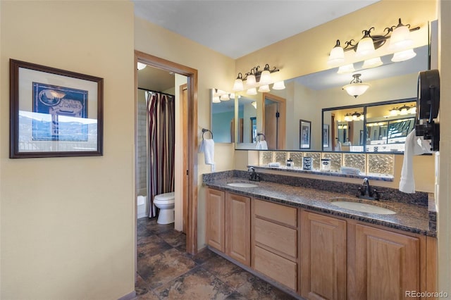 full bathroom with double vanity, toilet, and stone finish floors