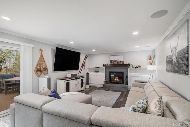 living room with recessed lighting, a glass covered fireplace, wood finished floors, and ornamental molding