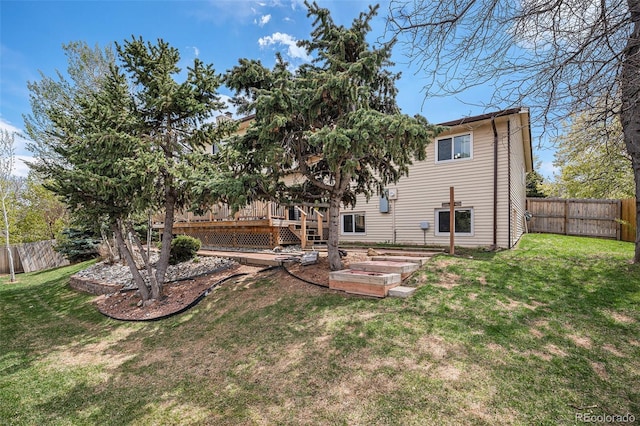 rear view of house featuring a lawn, a fenced backyard, and a deck