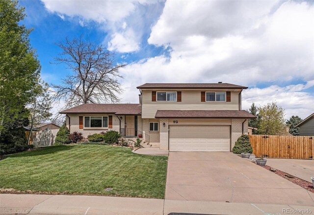 view of front facade featuring fence, concrete driveway, brick siding, and a garage