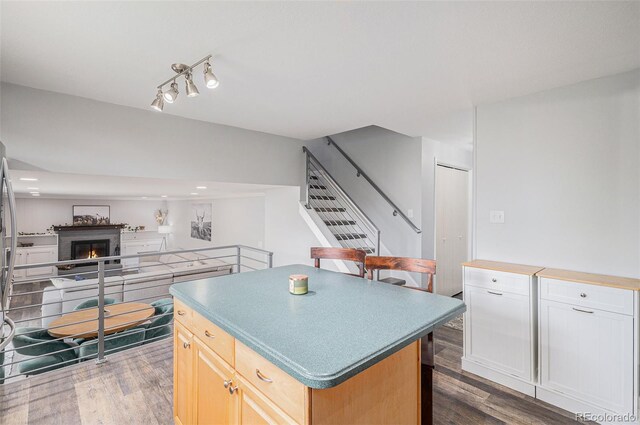 kitchen featuring open floor plan, dark wood-style flooring, a lit fireplace, and a kitchen island
