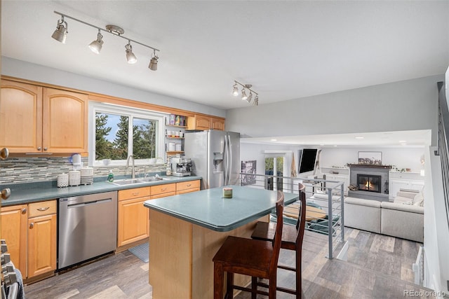 kitchen featuring a kitchen bar, light wood-style floors, stainless steel appliances, and a sink